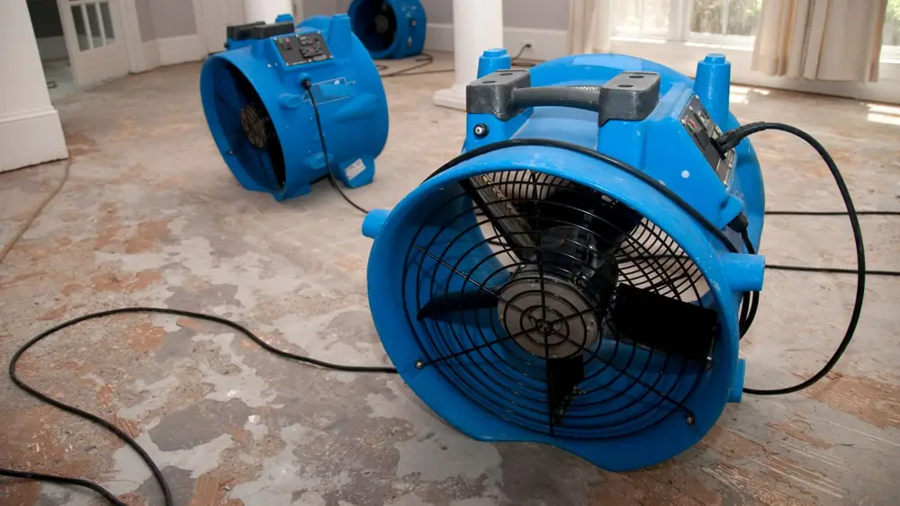 Blue air mover drying a concrete floor after a flood