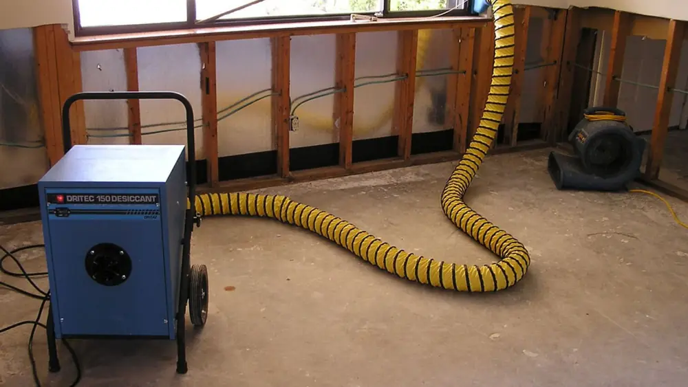 Dehumidifier with a duct hose in a room with open wall studs